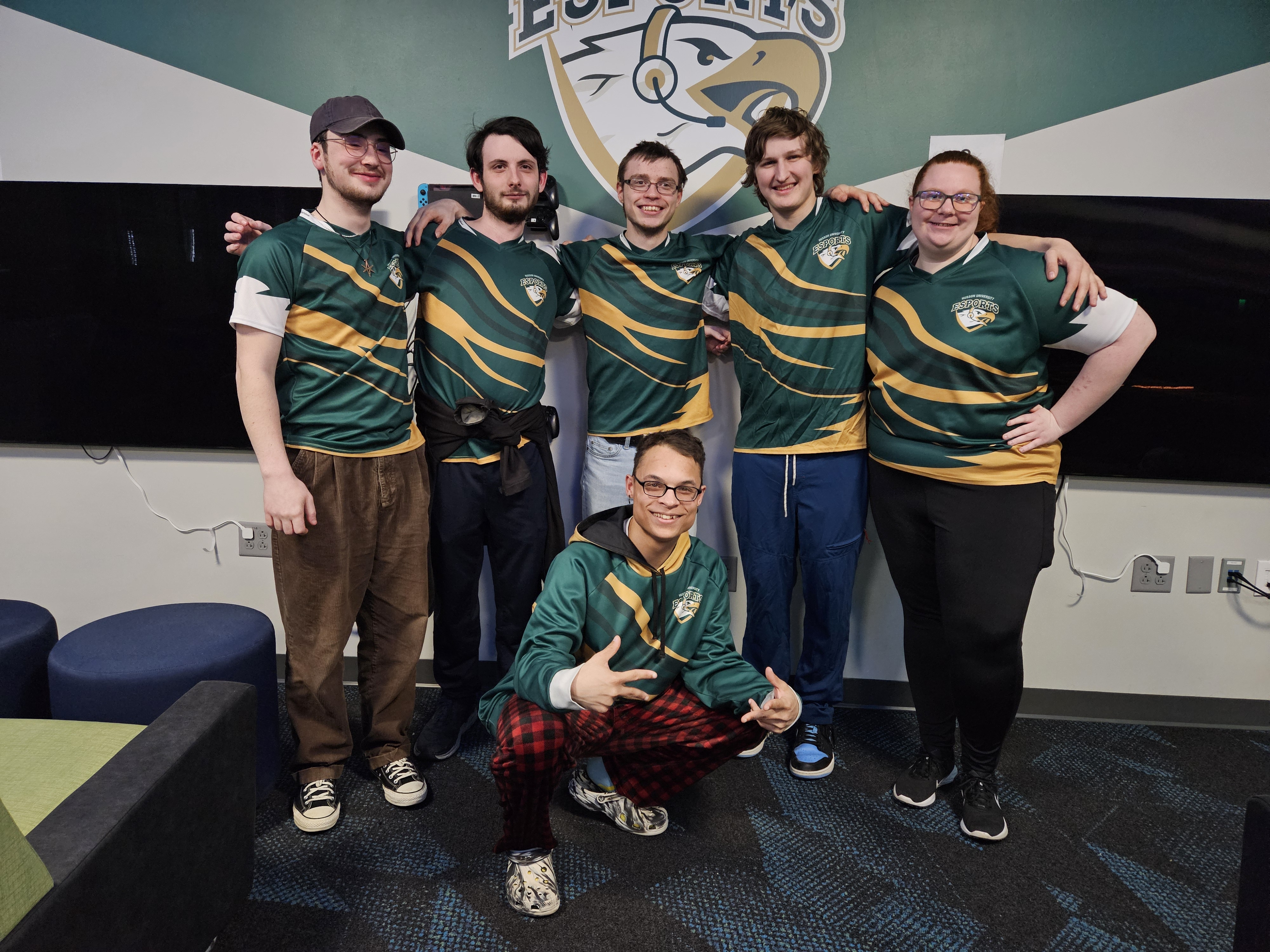 A group of six people wearing green Husson esports uniform shirts are shown.