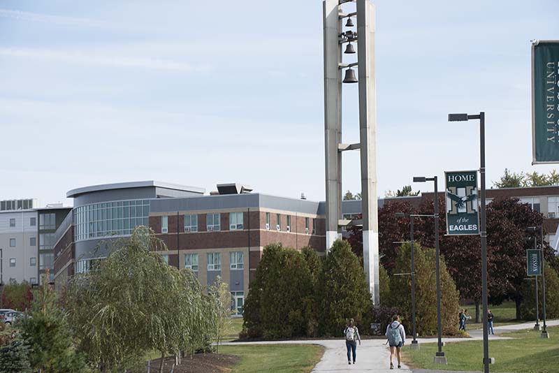 Students walk towards the Bell Tower on the campus of Husson University