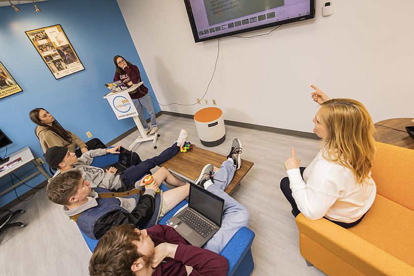 Students work in the One Circle Agency space with a faculty member