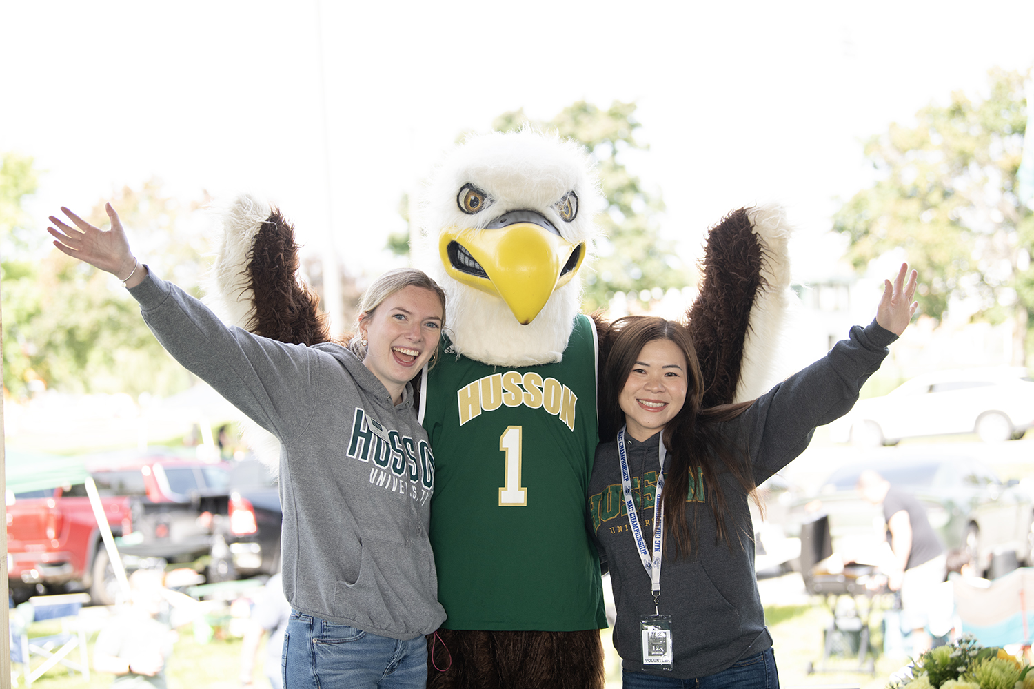 Smiling young women stand with Husson's mascot, a bald eagle.