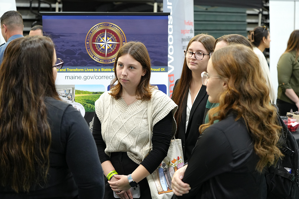 A group of young people in professional attire speak to law enforcement professionals in a gymnasium.