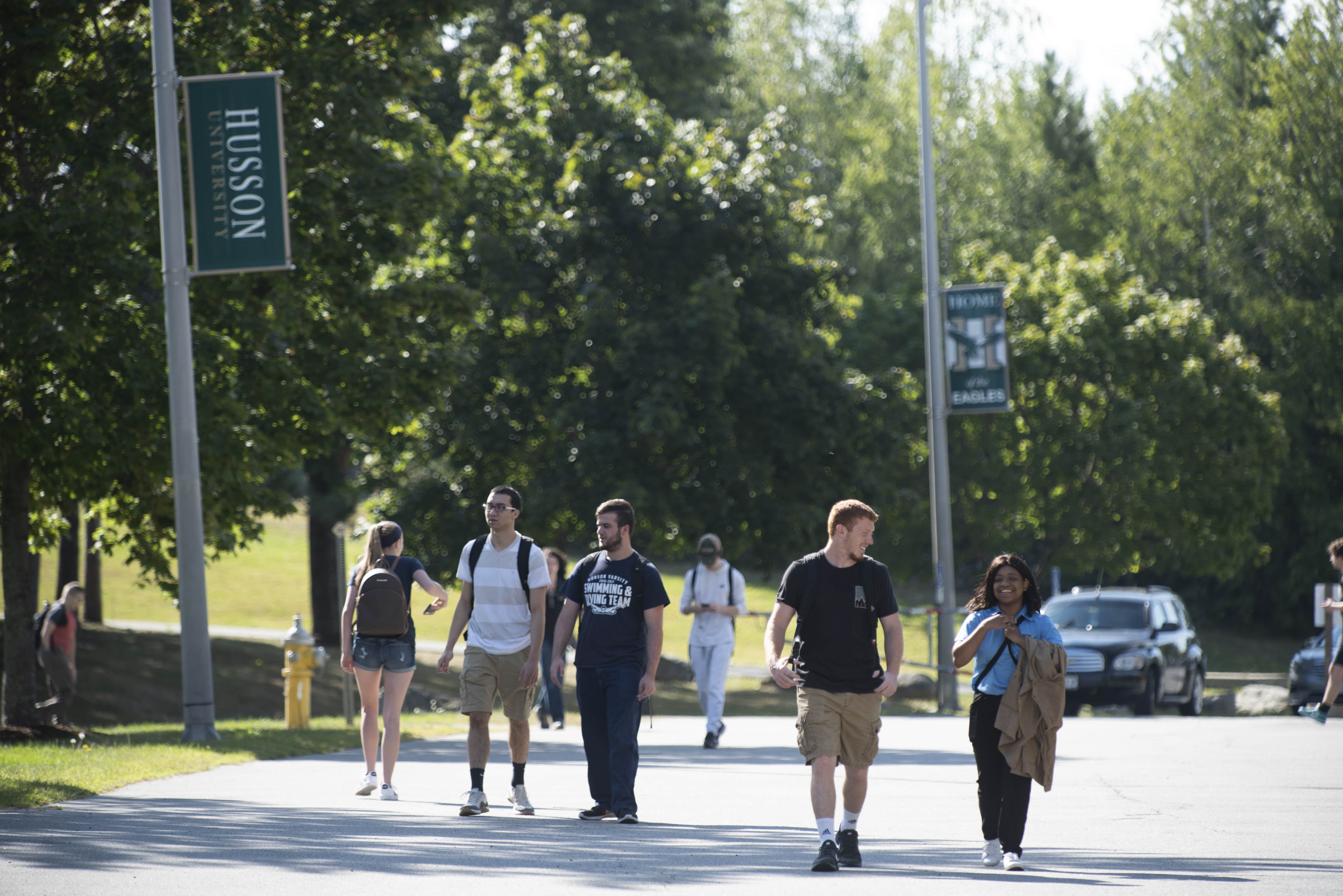 Multiple people walking outside through Husson University's campus.