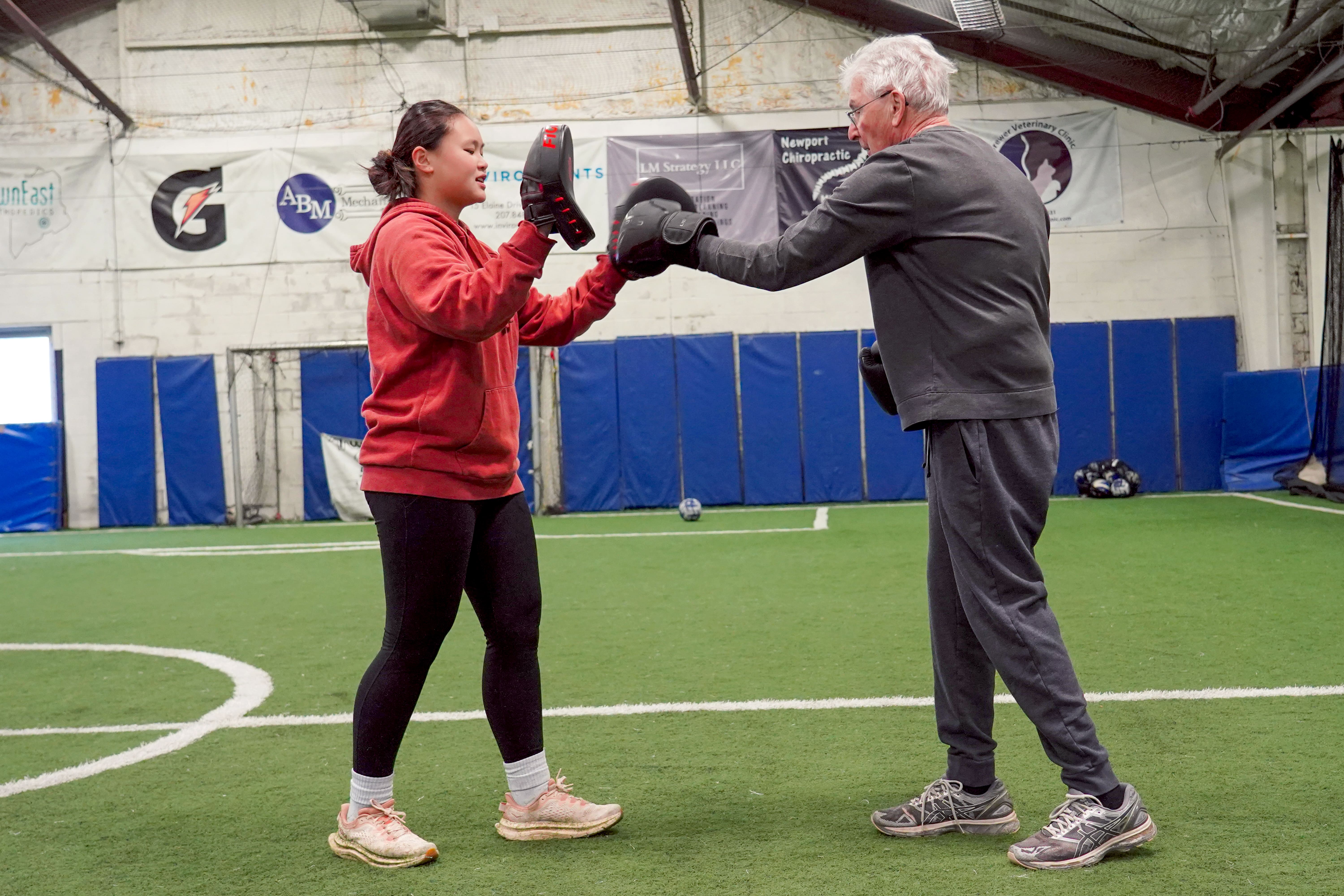 Husson student helps individual with a boxing drill.