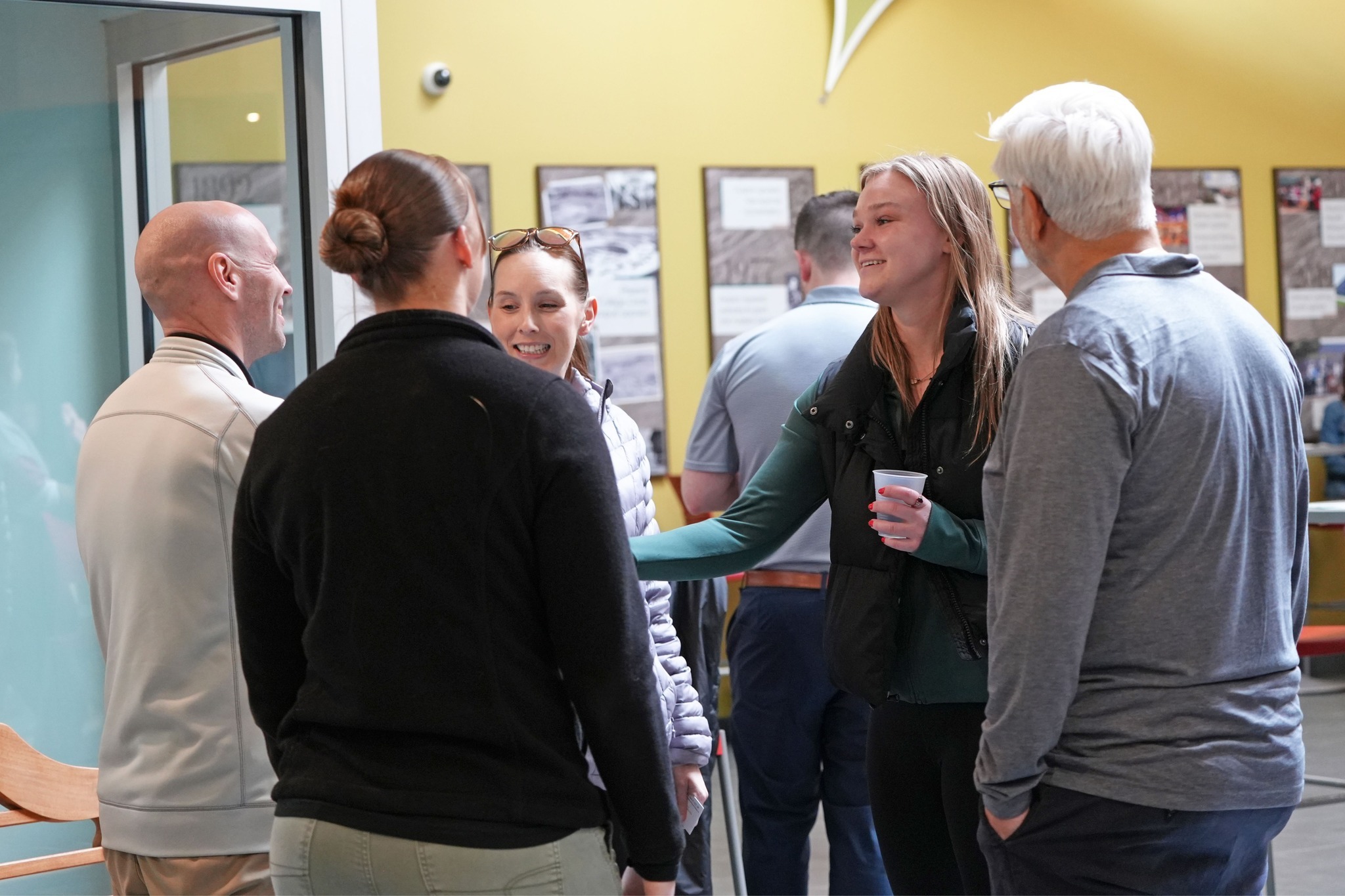 People stand around chatting in an open space with cups in hand.