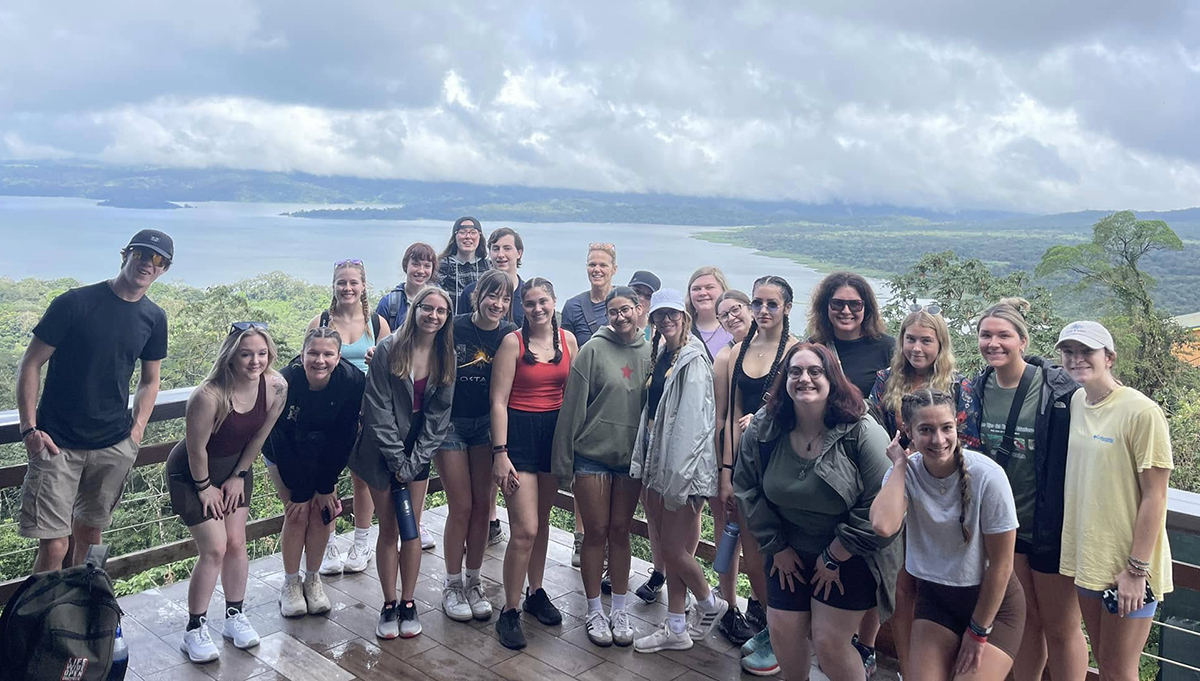 A group of young people are shown in a scenic photo.