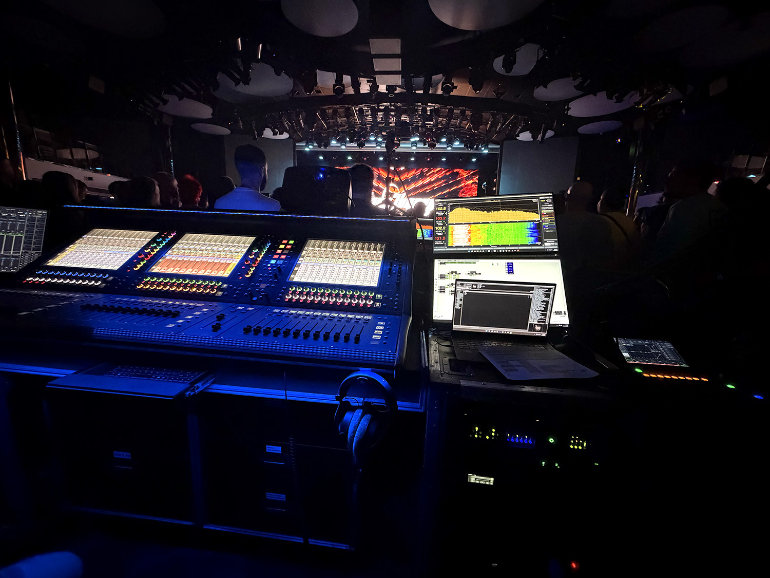 A soundboard lit up is shown. A stage can be seen in the background.