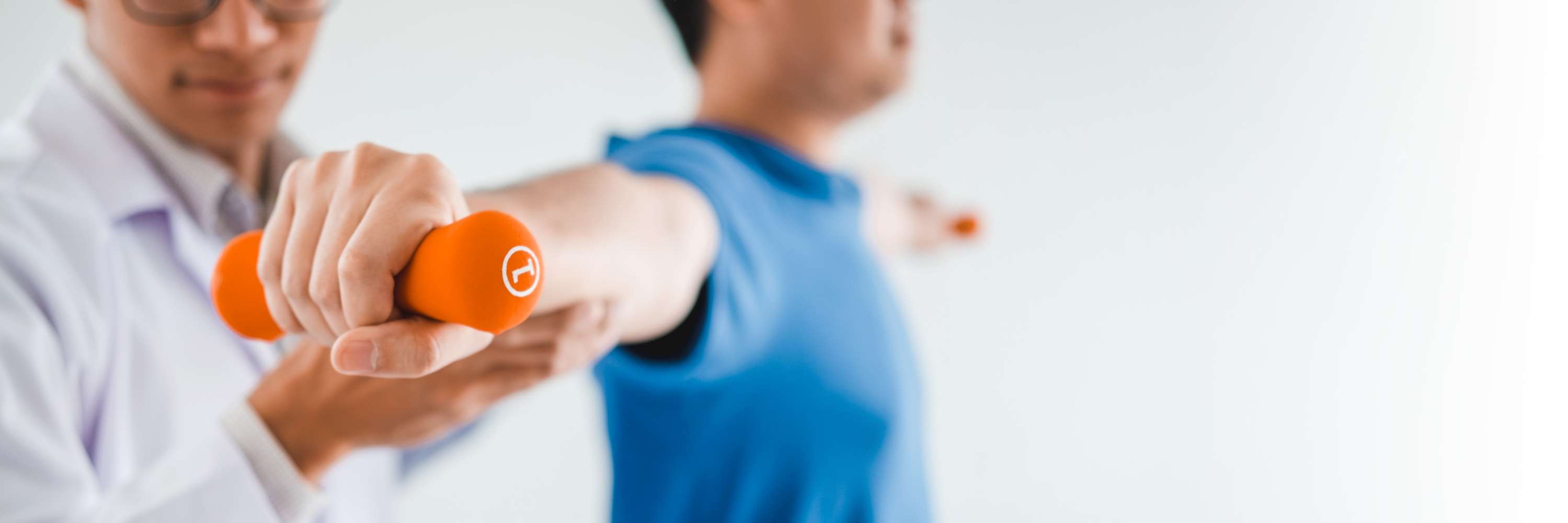 Healthcare professional helping a patient with a free-weight exercise.