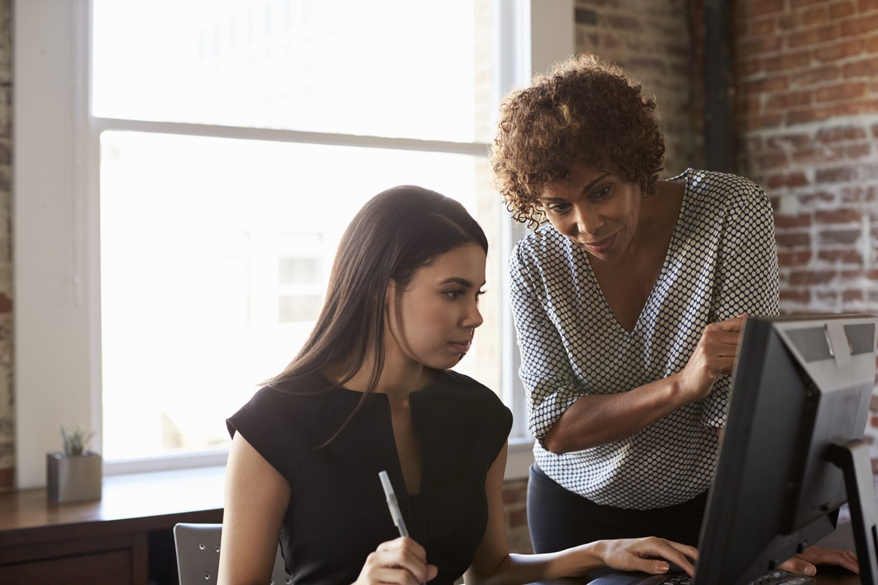 Two businesswomen working at a computer.