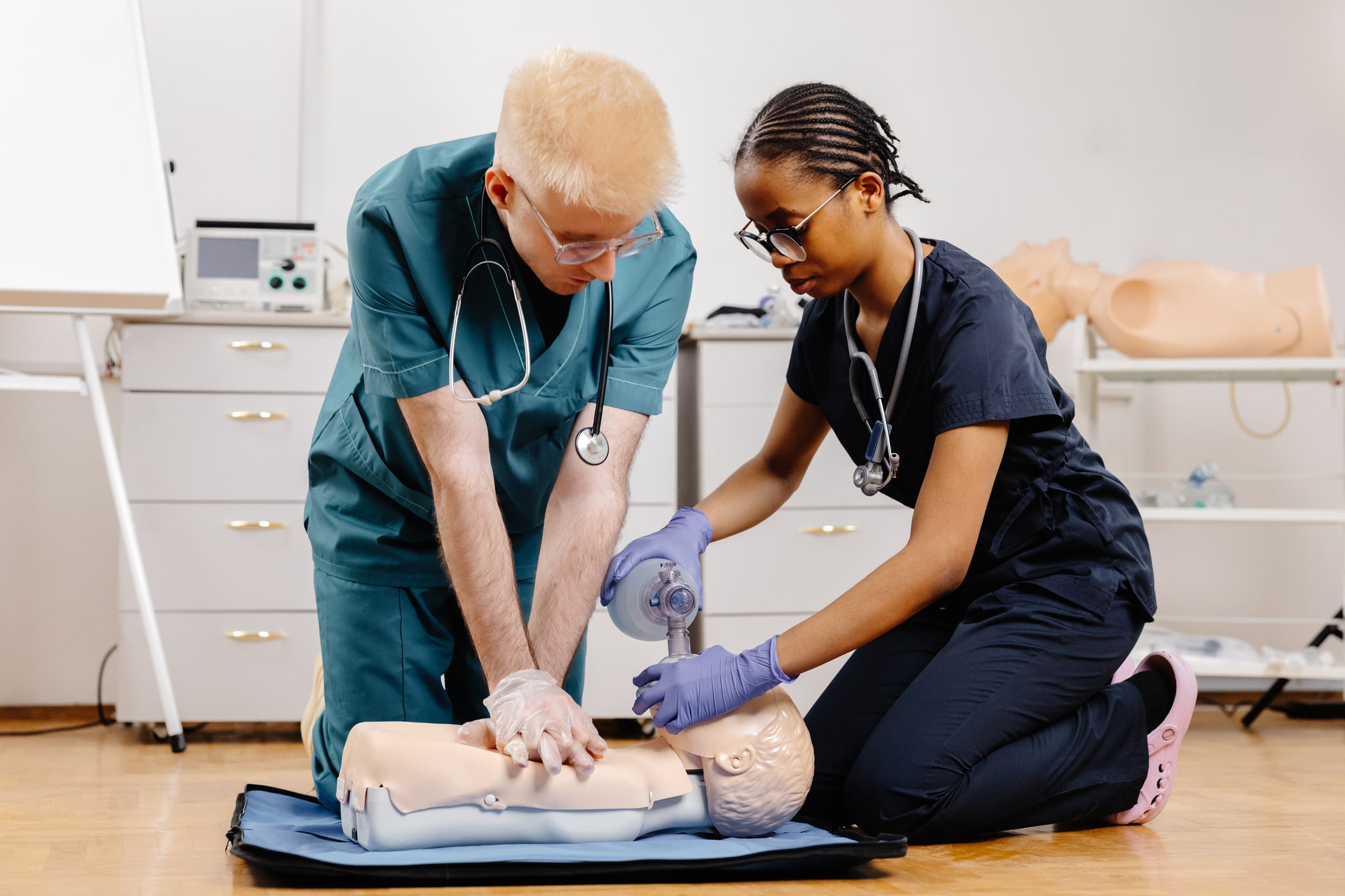 Two nurses perform CPR on a manikin.