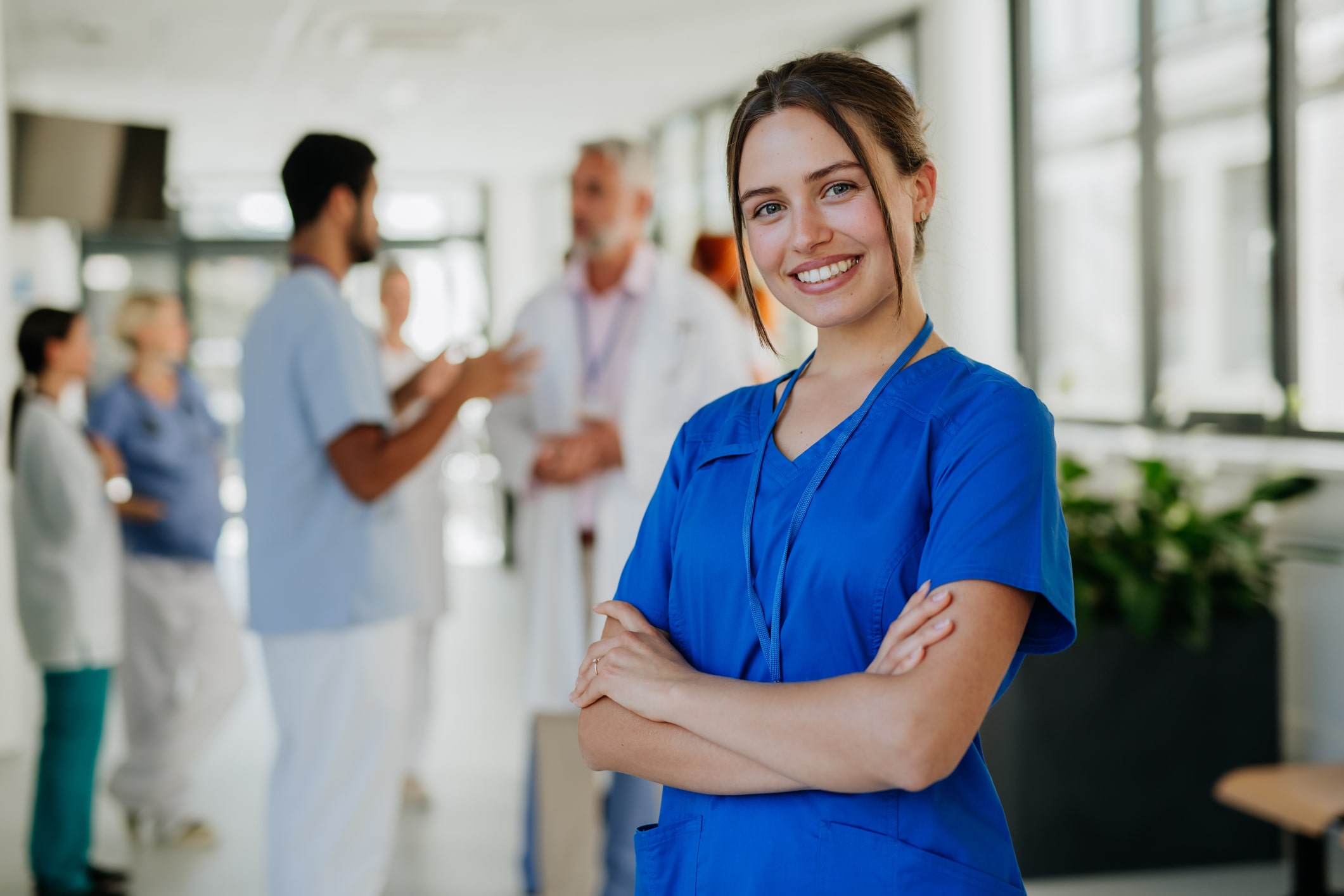 Nurse stands with arms folded while smiling.